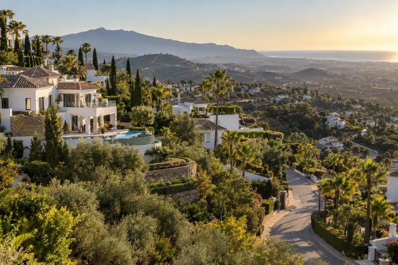 Urbanización residencial de lujo en Benahavís con villas blancas y vegetación mediterránea al atardecer