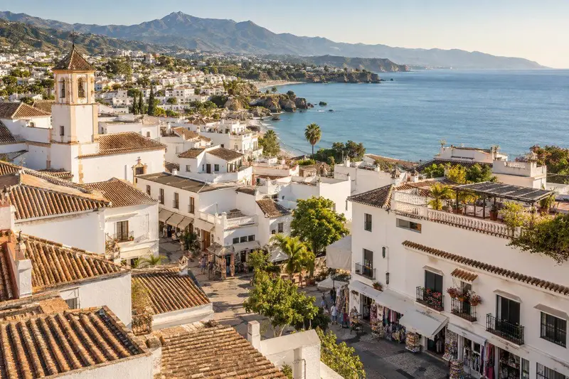 Vista aérea de un pueblo blanco andaluz junto al mar en Mijas, con tejados y pequeños comercios