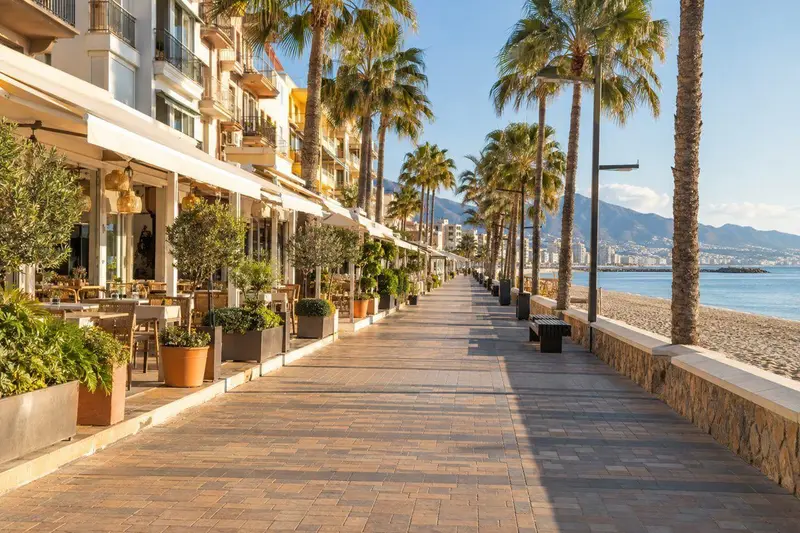 Paseo marítimo de Fuengirola con comercios locales y terrazas al sol